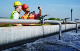 Two workers inspecting a bridge over a lake, part of water quality and quantity management