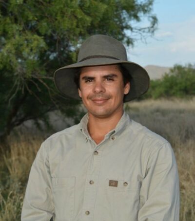 Headshot of Fernando Falomir dressed in a suit and wearing a cowboy hat, exuding a professional demeanor